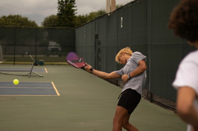 pickleball-game-action A player swinging a pickleball paddle during a game on an outdoor court