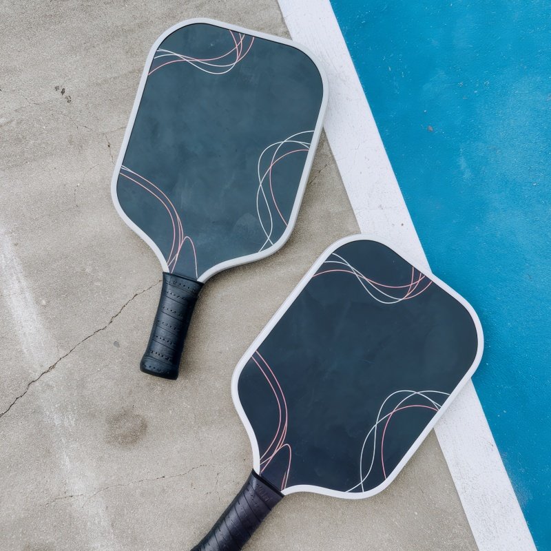 Elegant pickleball paddles for competitive and casual play Two sleek pickleball paddles with modern abstract designs placed on a court