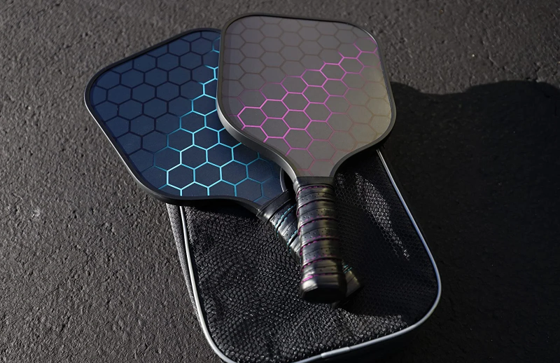 Two modern pickleball paddles with hexagonal patterns and neon highlights on a black cover