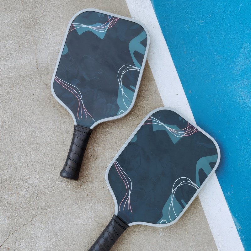Modern pickleball paddles for stylish gameplay Two stylish pickleball paddles with abstract designs placed on a court