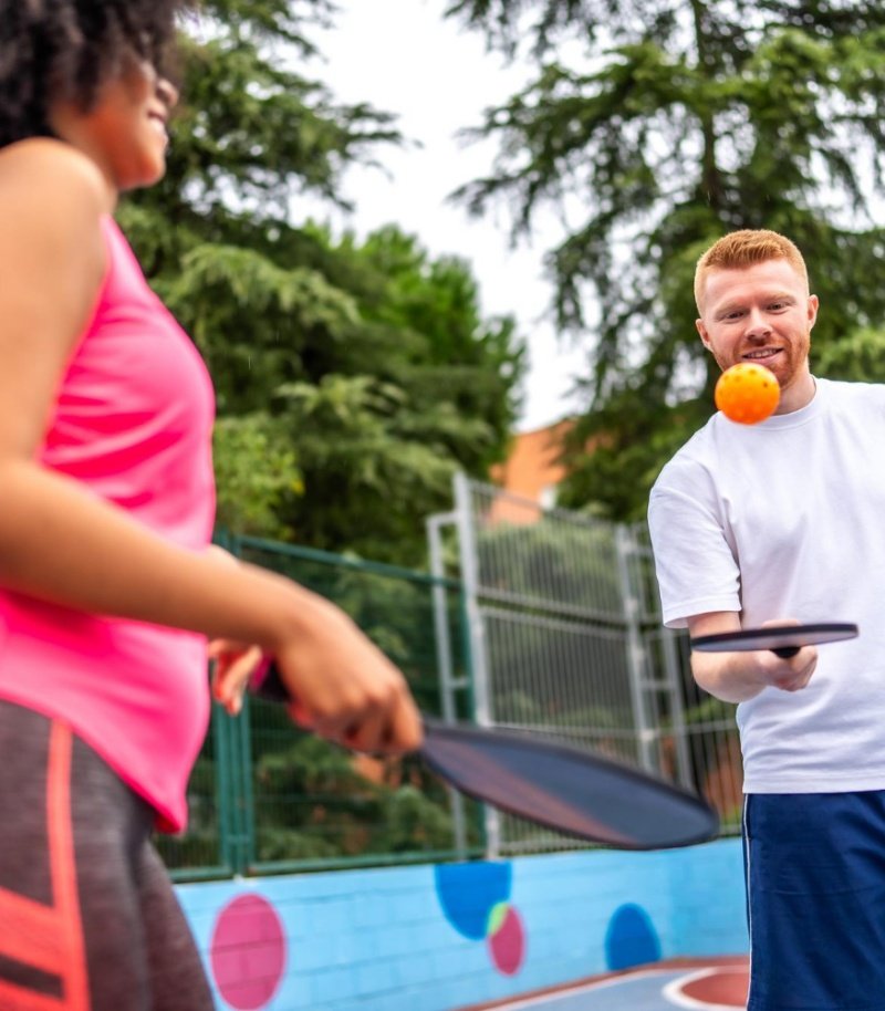 Pickleball game on an outdoor court with a focus on fun and engagement Two players enjoying a lively game of pickleball on an outdoor court