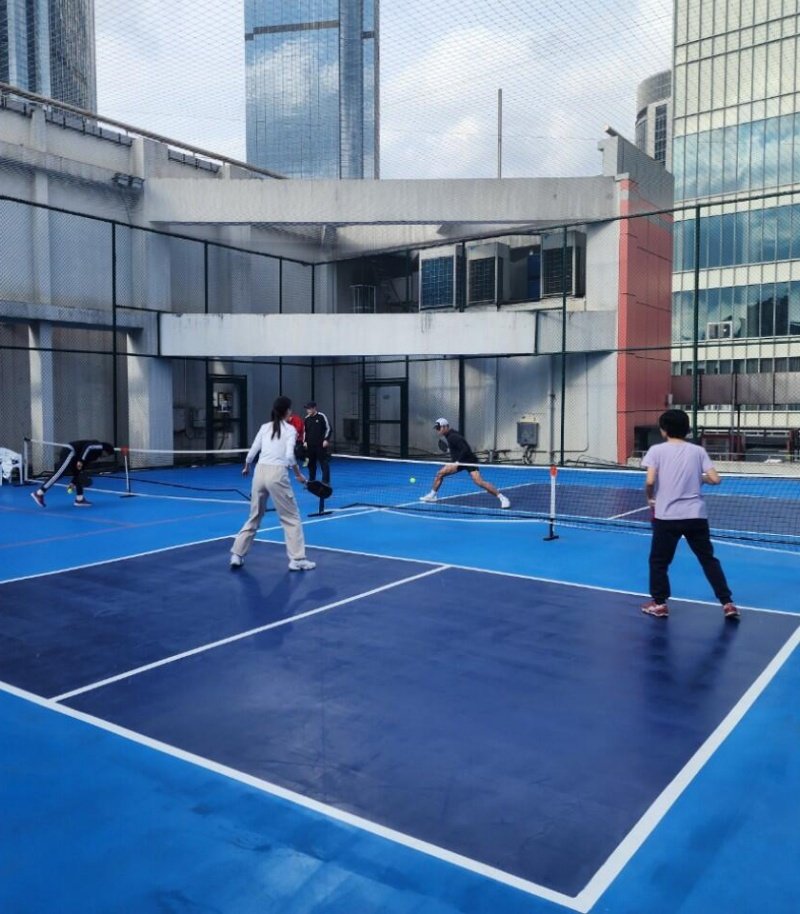 Group playing pickleball on a rooftop court surrounded by city buildings