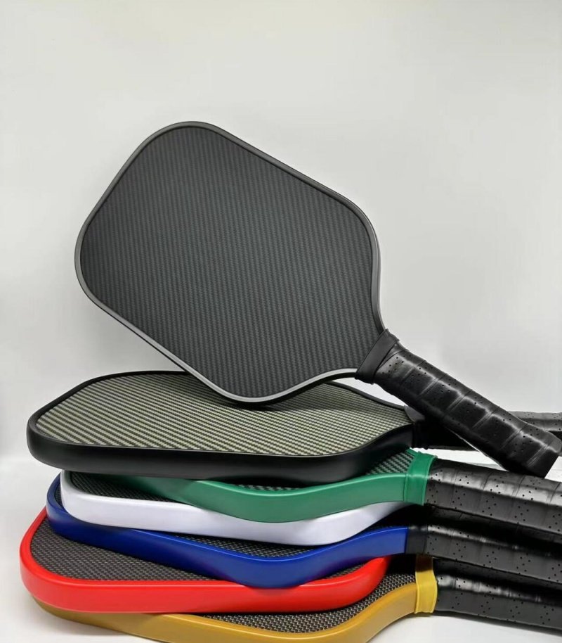 Variety of premium pickleball paddles with carbon fiber designs Stack of colorful pickleball paddles with carbon fiber surfaces, displayed on a white background.