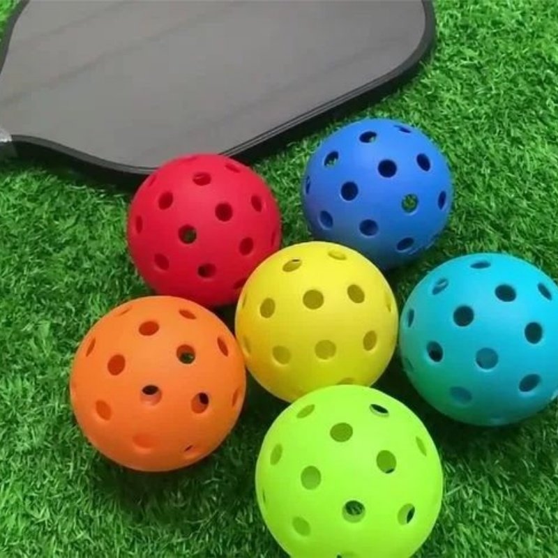Colorful pickleball balls and paddle Colorful pickleball balls on grass next to a paddle