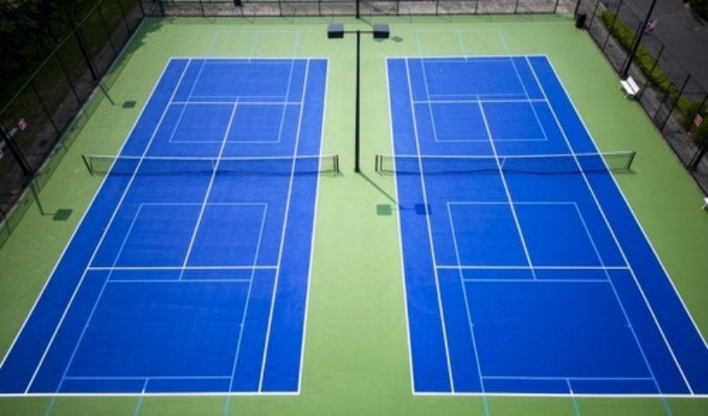 Aerial view of two blue pickleball courts with green surroundings