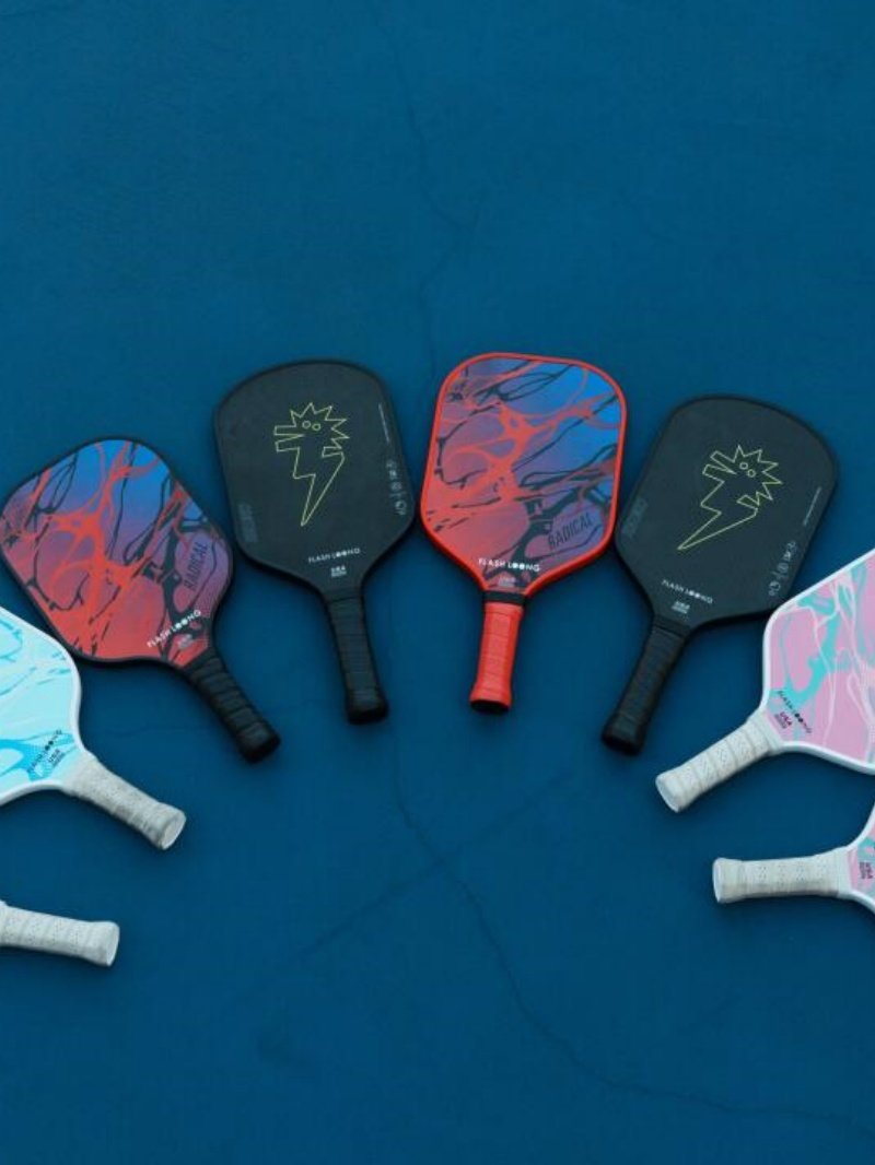 Colorful pickleball paddles on court Six colorful pickleball paddles with abstract designs laid out on a blue court