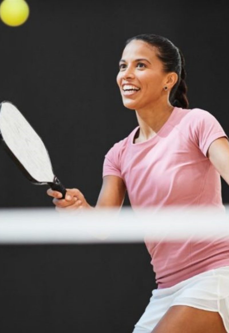 Enjoying a pickleball match Smiling female pickleball player preparing a shot