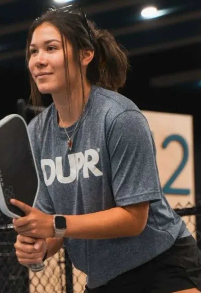 Focused Pickleball Player Ready to Play Female pickleball player in a DUPR shirt preparing for a game