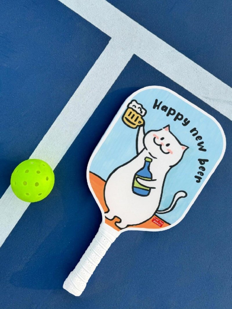 Pickleball paddle with cartoon cat design and ball