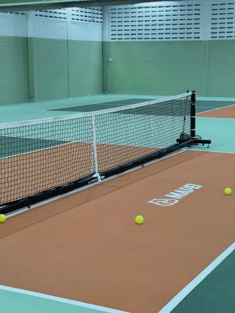 Indoor pickleball court setup Indoor pickleball court with net and yellow balls on the floor