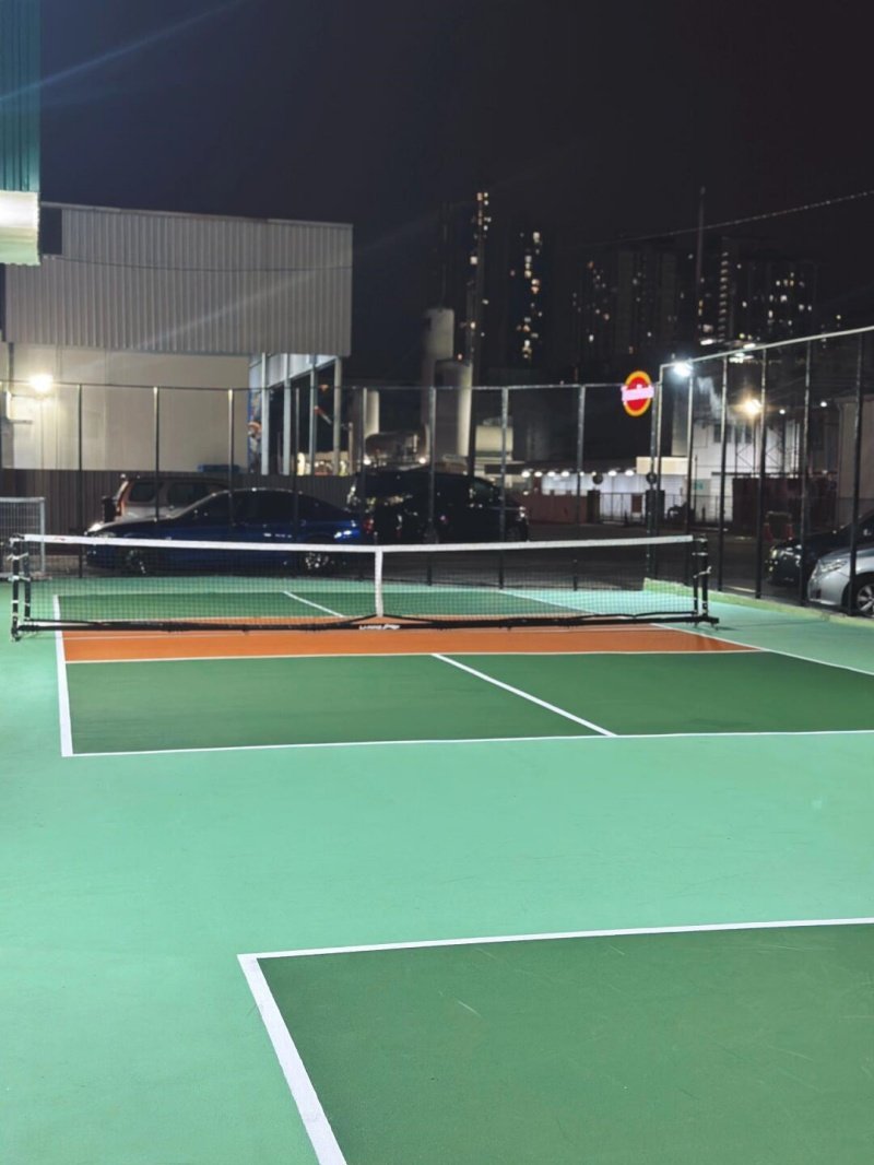Nighttime pickleball courts lighting Outdoor pickleball courts illuminated at night with city buildings in the background