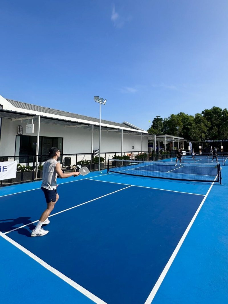 Outdoor Pickleball Match Player on a blue pickleball court preparing to hit the ball