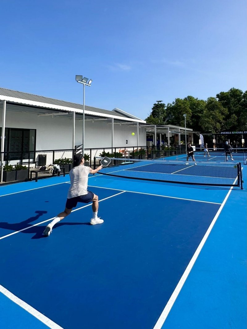 Pickleball Action Shot Pickleball player lunging to hit the ball on a blue outdoor court