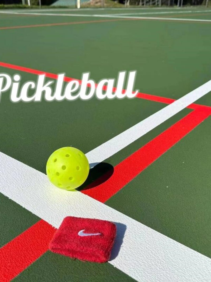 Pickleball Court Close-Up Yellow pickleball and red wristband on a green court with white and red lines