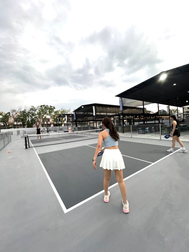 Pickleball Game Under the Clouds Players competing in a pickleball match on an outdoor court under cloudy skies