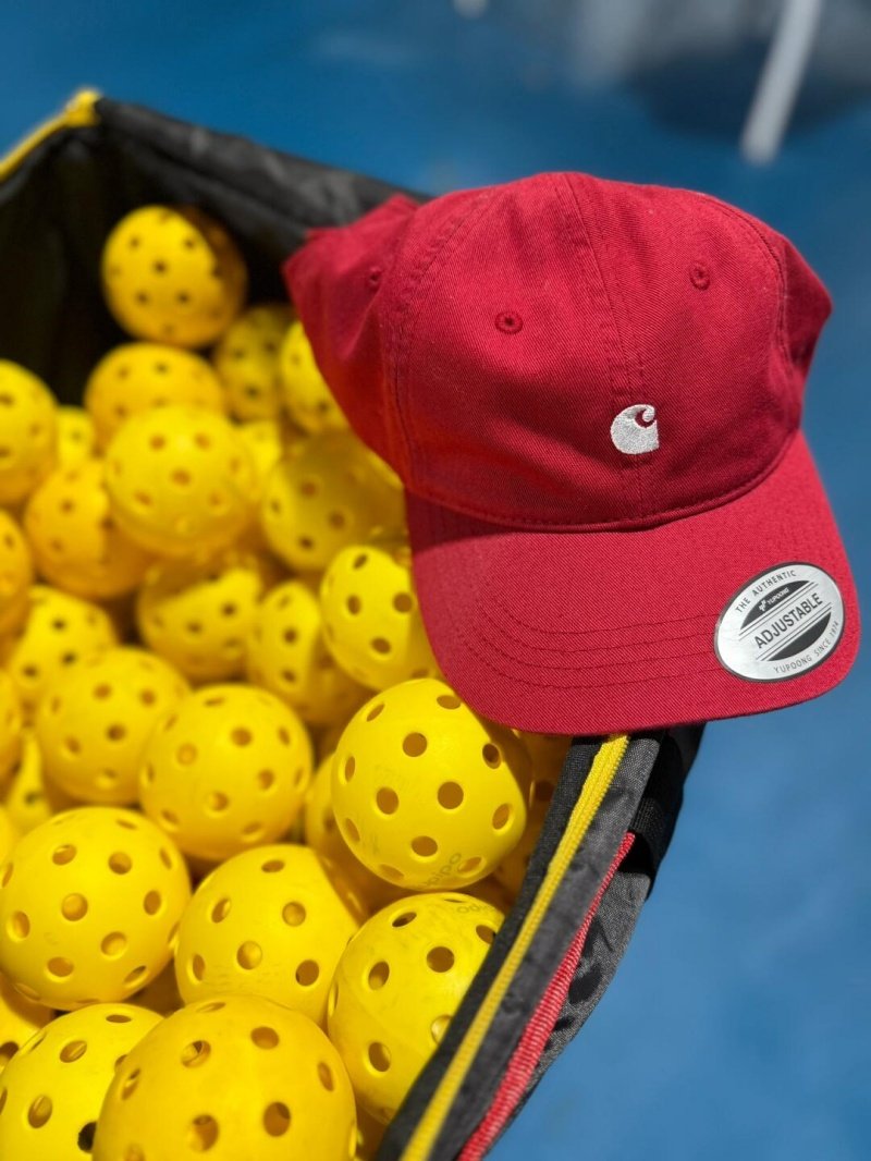 Pickleball Gear and Accessories Bag full of yellow pickleballs with a red cap on top