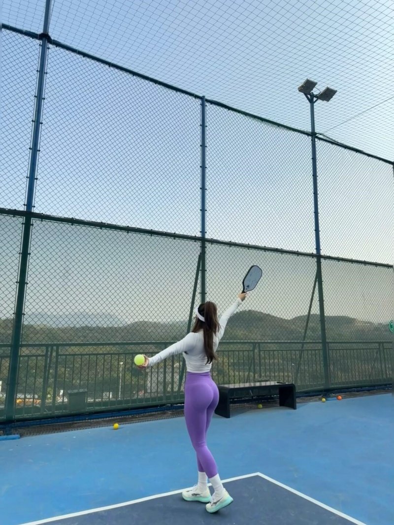 Pickleball Serve Action Woman preparing to serve in a pickleball match on an outdoor court