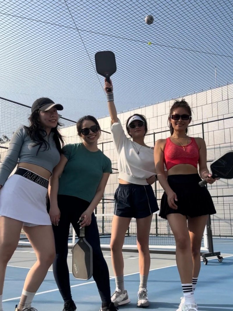 Pickleball Squad Fun Four women posing on a pickleball court with paddles