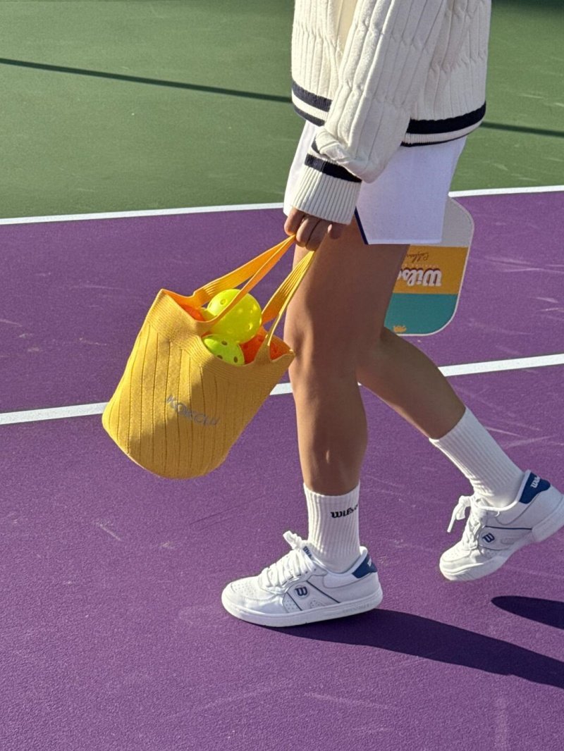 Pickleball court style Player carrying pickleball gear on vibrant purple and green court