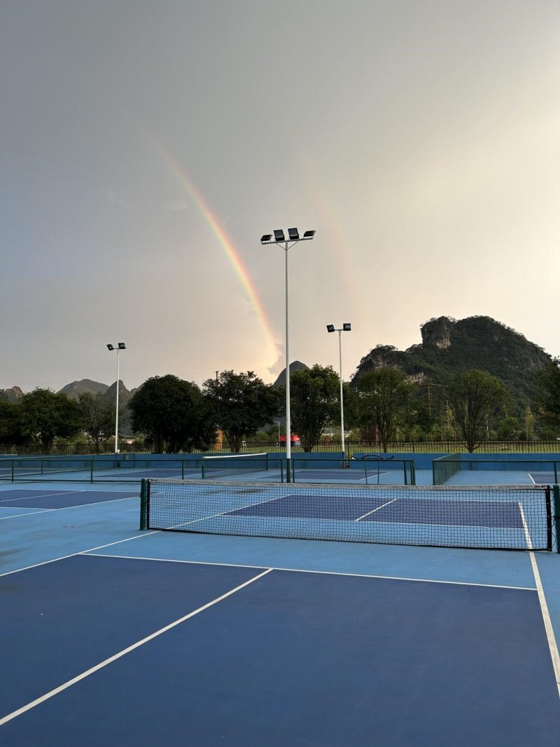 Pickleball courts under a rainbow Scenic outdoor pickleball courts with a rainbow in the sky