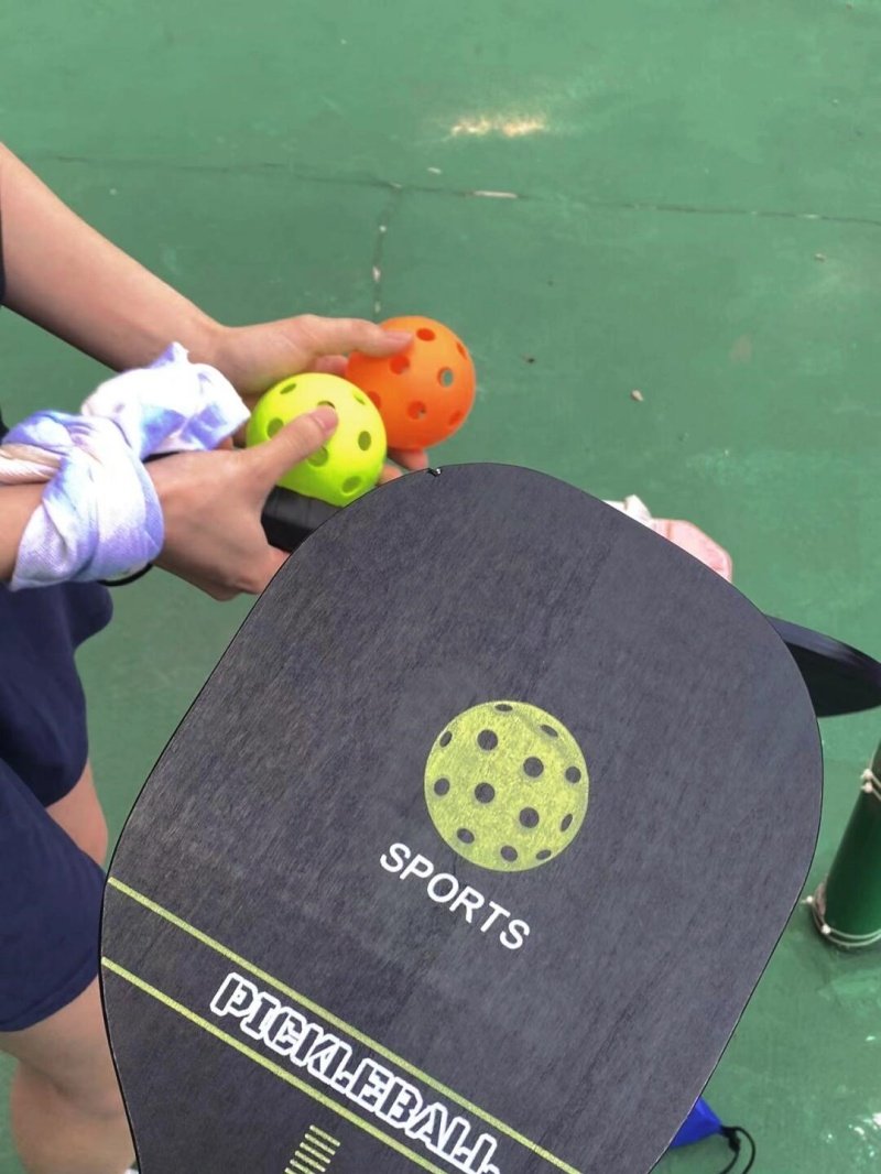 Close-up of a pickleball paddle and colorful pickleballs