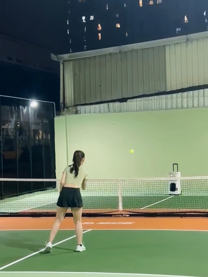 Pickleball training session Female pickleball player practicing at night with a ball machine