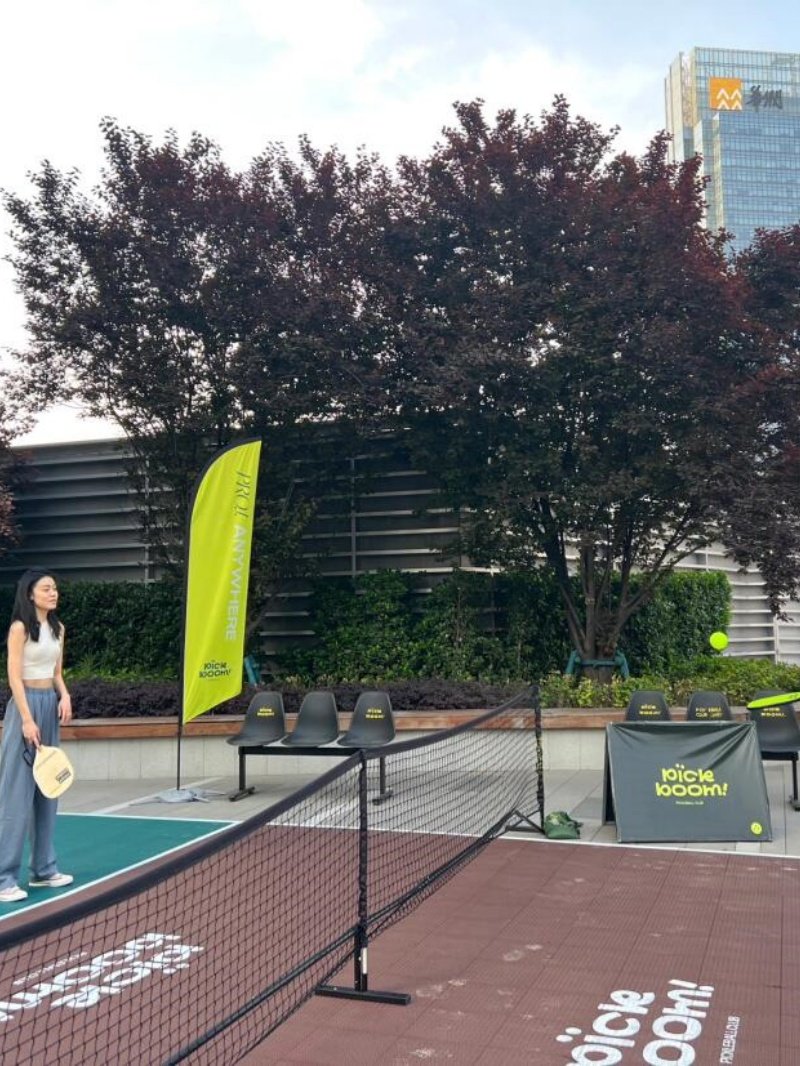 Outdoor pickleball court setup with player and promotional banners