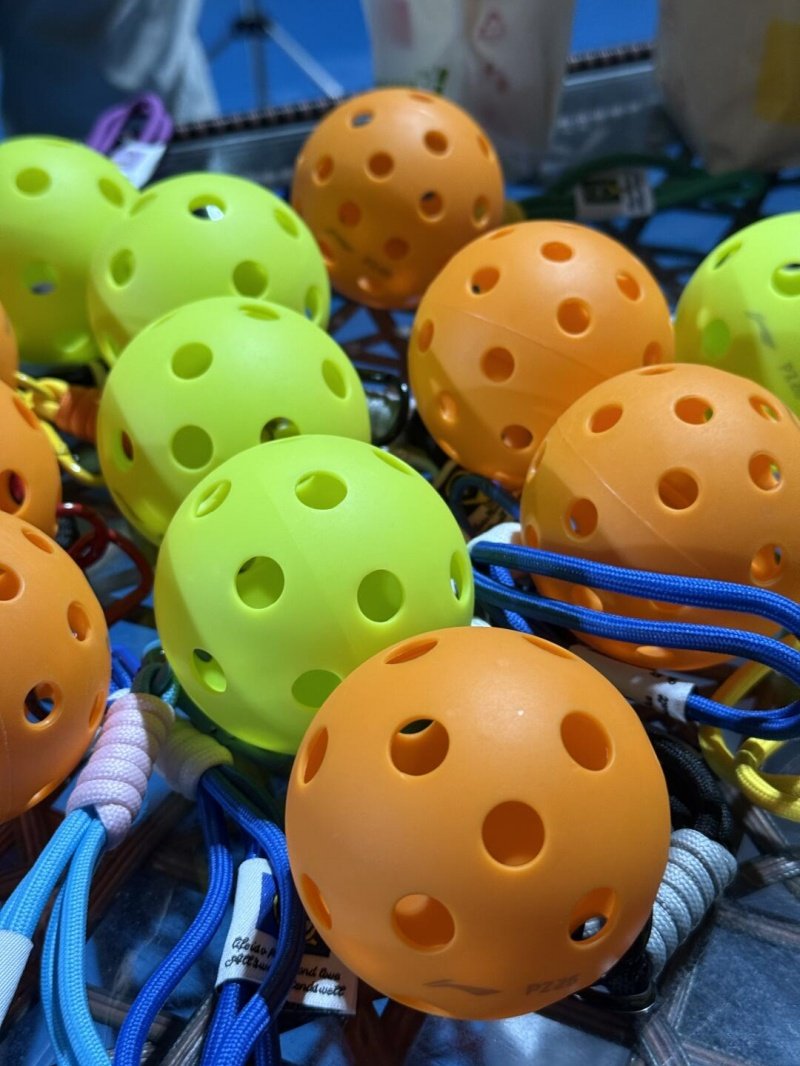 Vibrant Pickleball Equipment Close-up of orange and green pickleballs with colorful cords