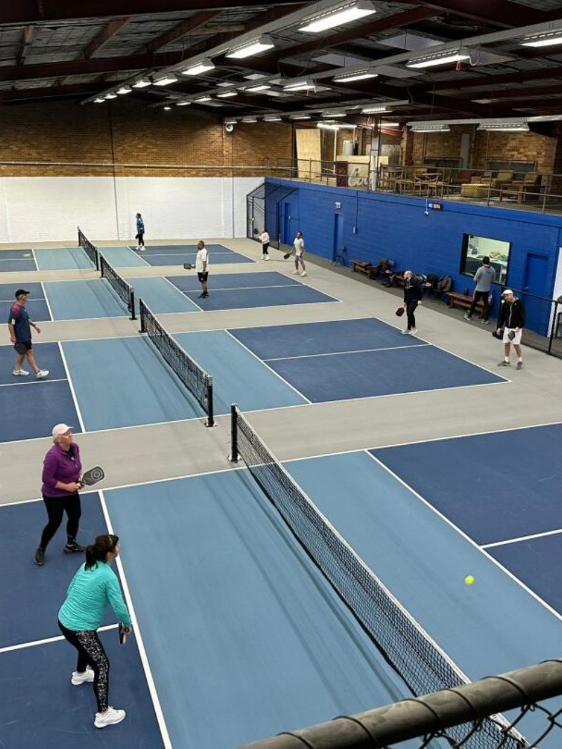 Indoor pickleball facility with multiple courts and active players