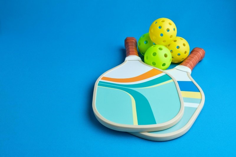 Colorful Paddle Set Colorful pickleball paddles with green and yellow balls on blue background