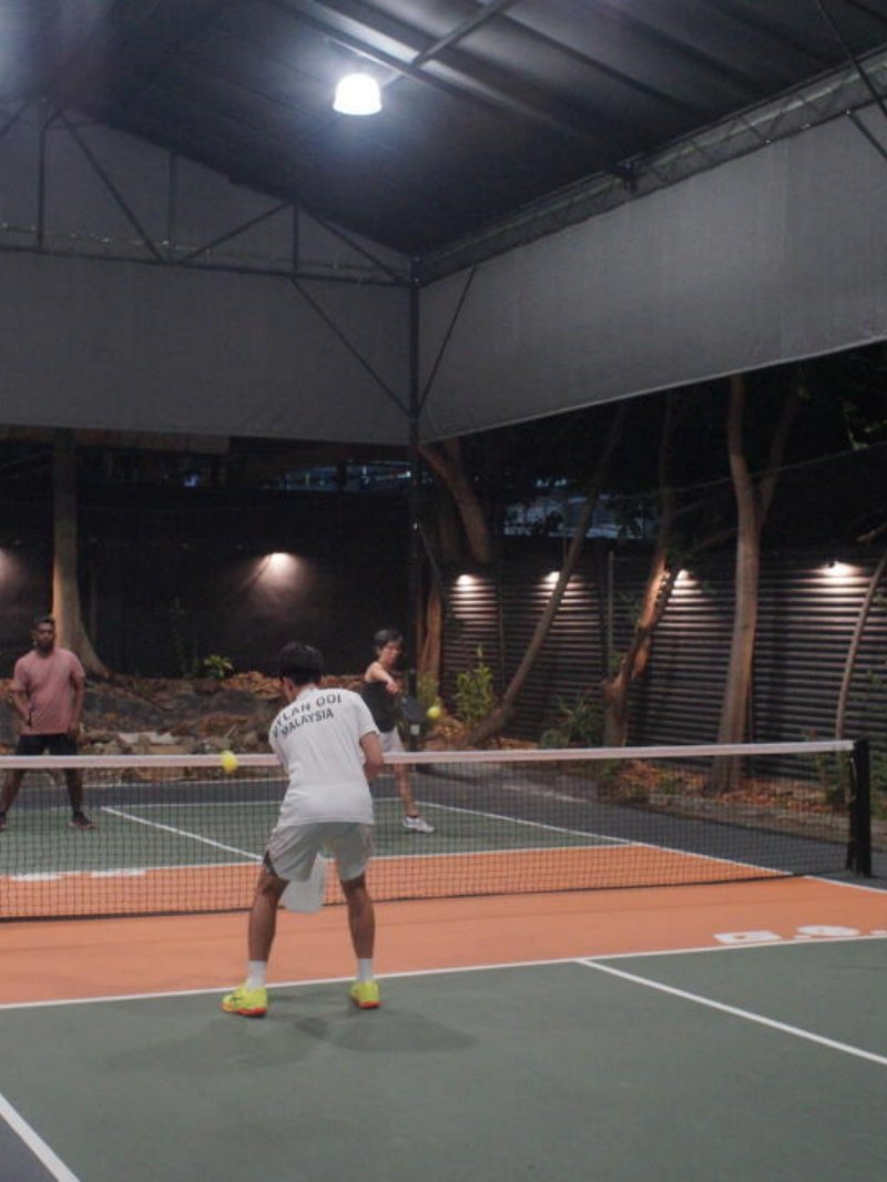 Evening Pickleball Rally Doubles pickleball match under lights on outdoor covered court at night