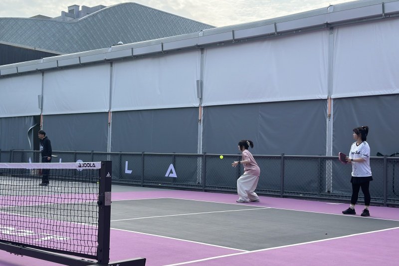 Outdoor Pickleball Game People playing pickleball on outdoor court with purple surface