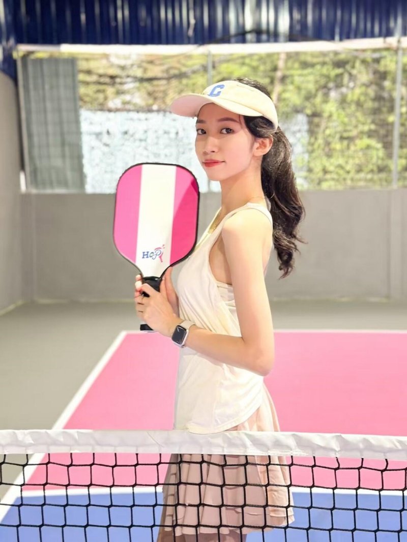 Pickleball Court Portrait Female player holding pink pickleball paddle on vibrant court