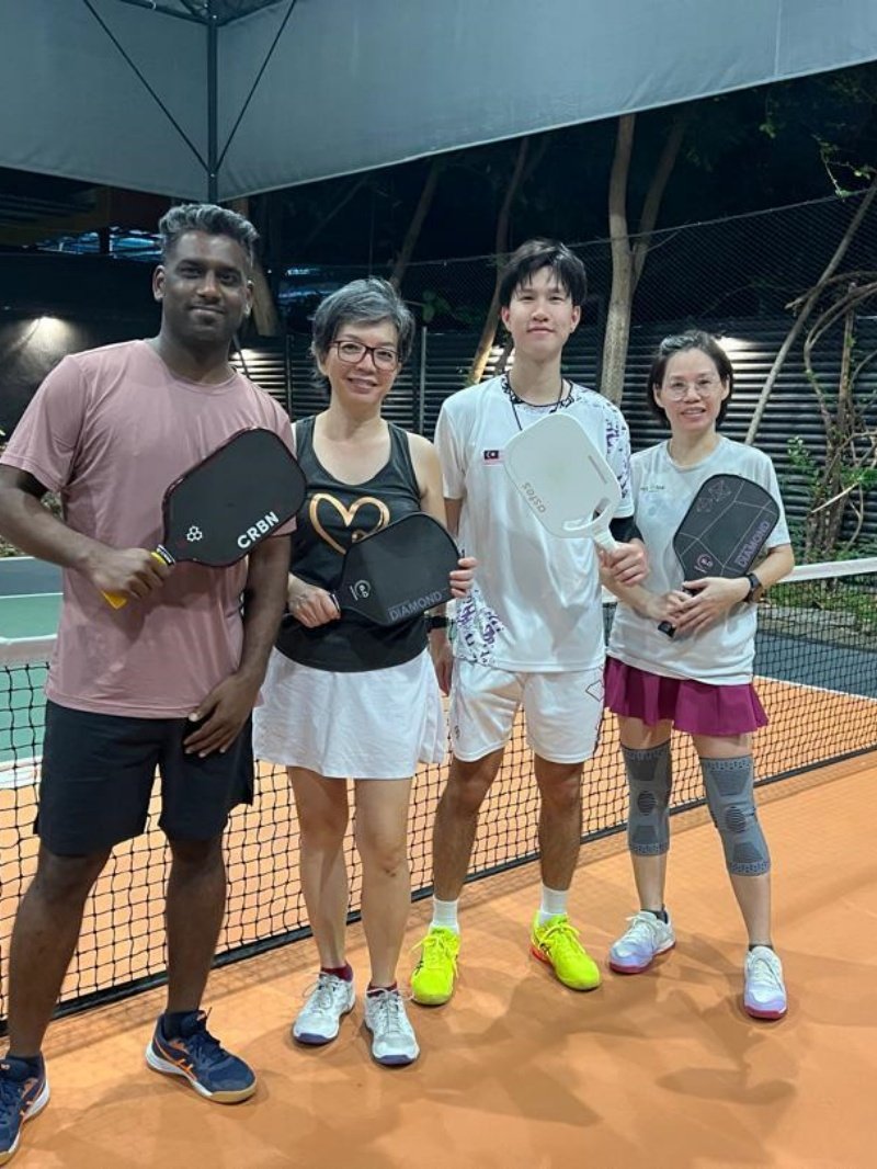 Pickleball Team Photo Group of four pickleball players posing with paddles on indoor court