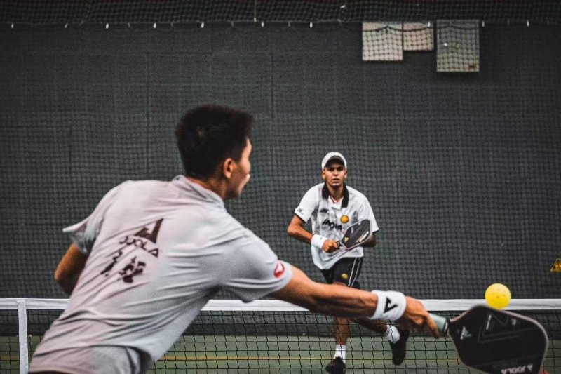 Pickleball doubles action Two players in a pickleball match, one hitting a shot