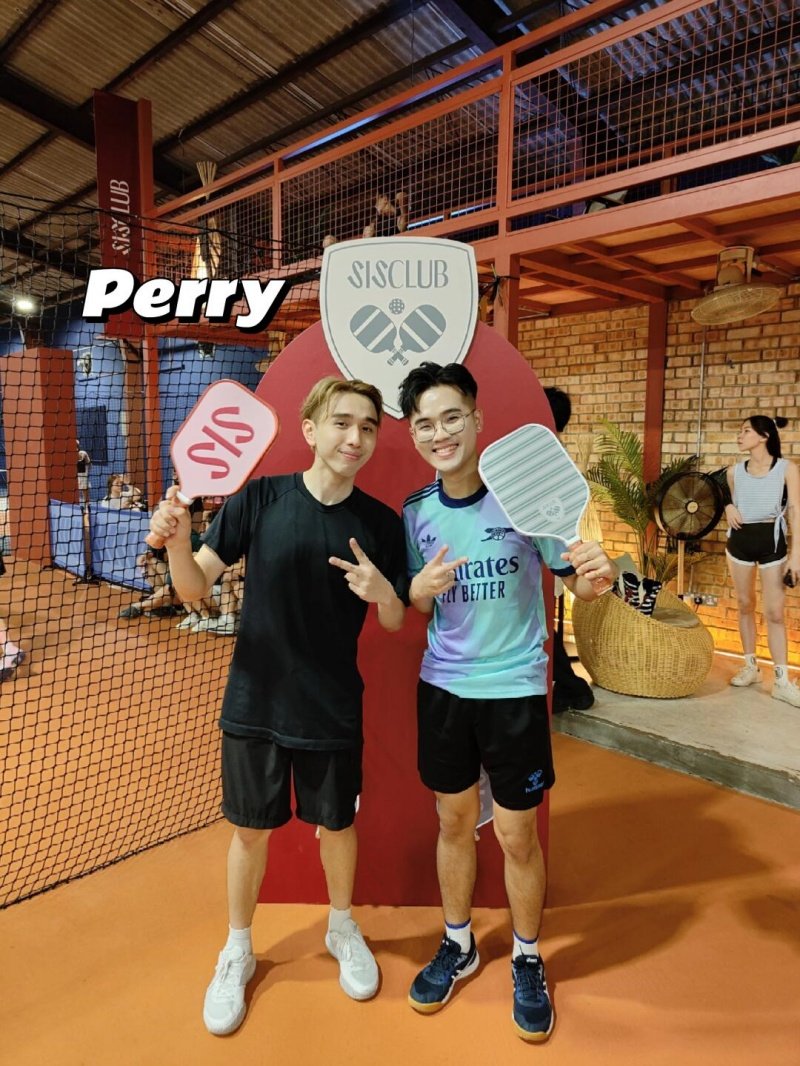 Players at SISClub Two players posing with pickleball paddles at SISClub court, one labeled Perry