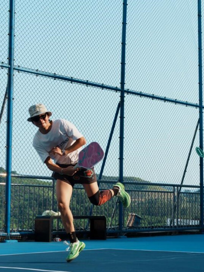 Rooftop Pickleball Jump Athletic pickleball player mid-air during outdoor match on rooftop court