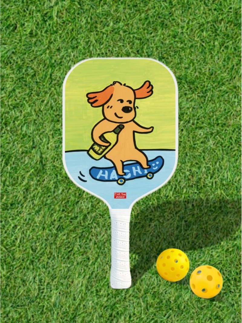 Skater Dog Paddle Pickleball paddle with cartoon dog on skateboard and yellow balls on grass
