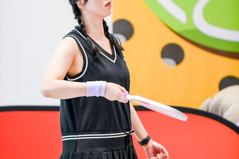Woman Playing Pickleball Female pickleball player in black outfit holding white paddle