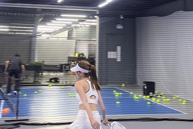 indoor-pickleball-practice Woman practicing pickleball indoors, wearing white sportswear