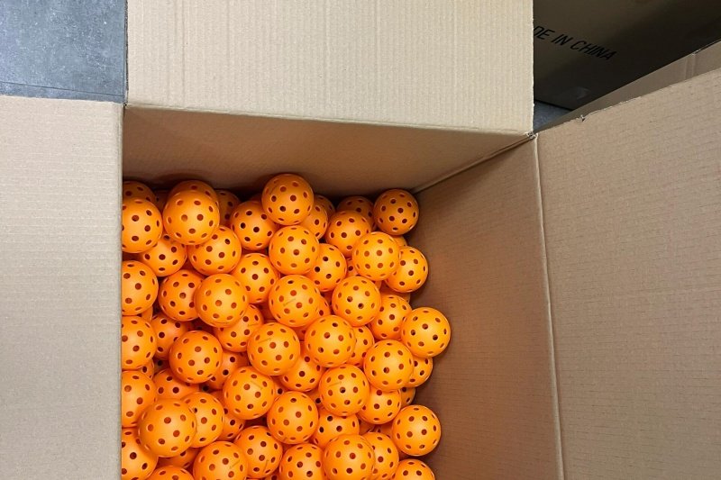 Cardboard box filled with bright orange pickleballs