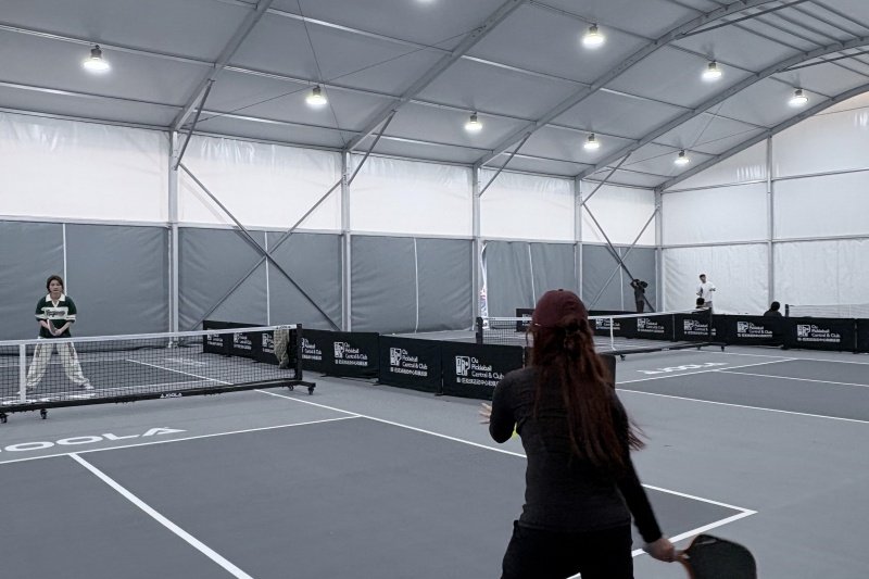 Indoor pickleball match under large covered court