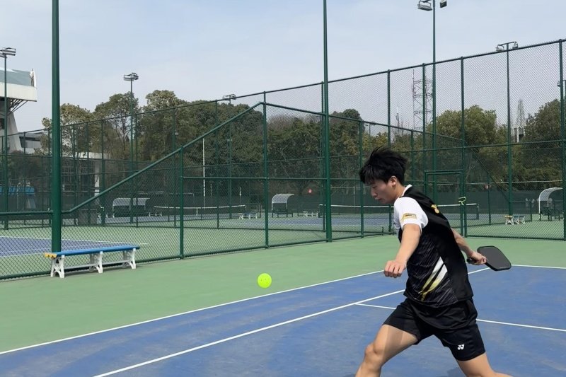 Pickleball Action Shot Player lunging to hit pickleball on court