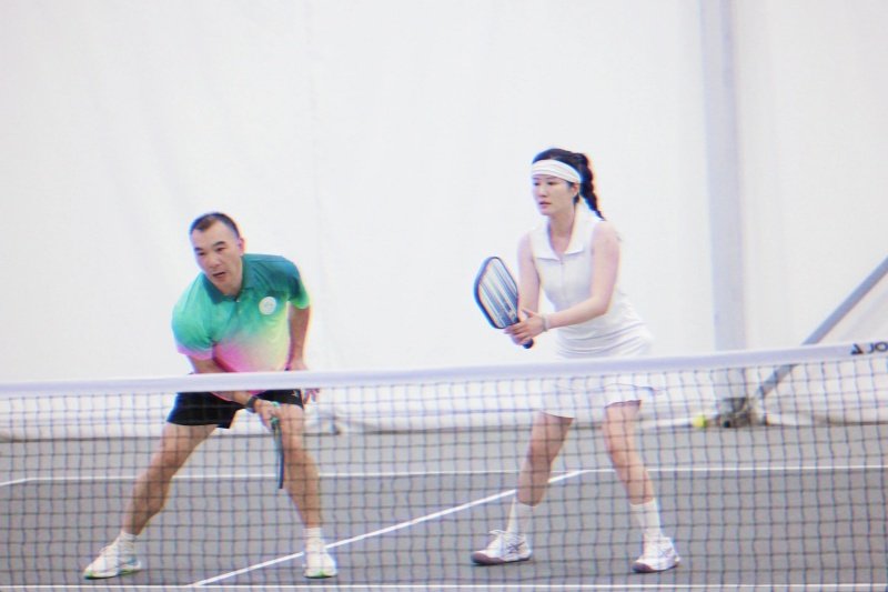 Pickleball Doubles Team Mixed doubles team ready at net in indoor pickleball match