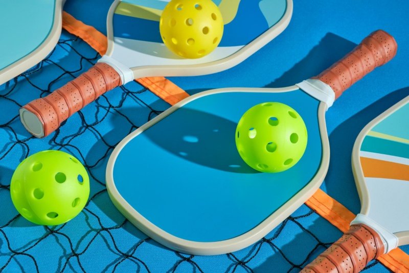 Colorful pickleball paddles and balls arranged on court
