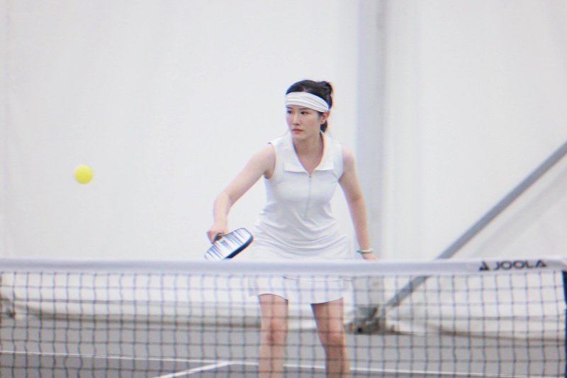 Pickleball Player in Action Focused female athlete playing pickleball near net