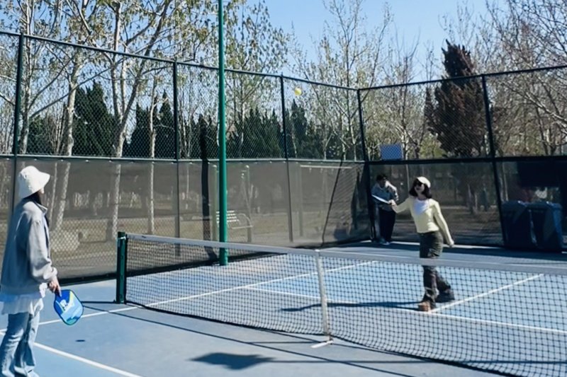 Pickleball Rally Two players hitting a pickleball over the net on outdoor blue court