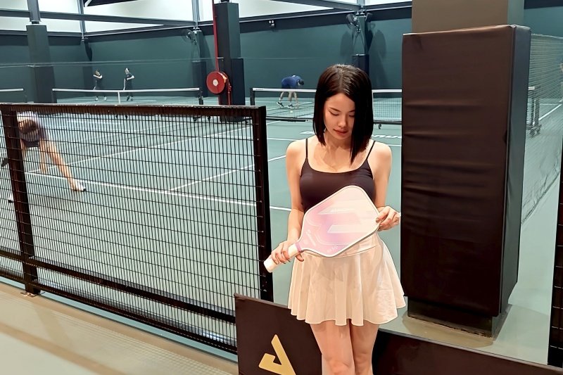 pickleball-court-action Woman holding a pickleball paddle with players in the background